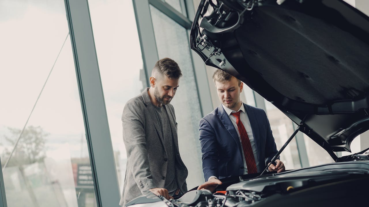 Crafting Captivating Headlines: Your awesome post title goes here Two men inspecting a car's engine hood in a dealership showroom.