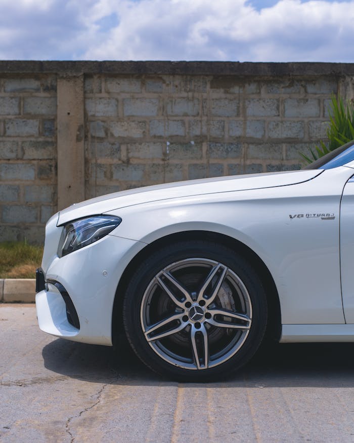 Side view of a white Mercedes-Benz E-Class with V8 turbo engine on a sunny day.