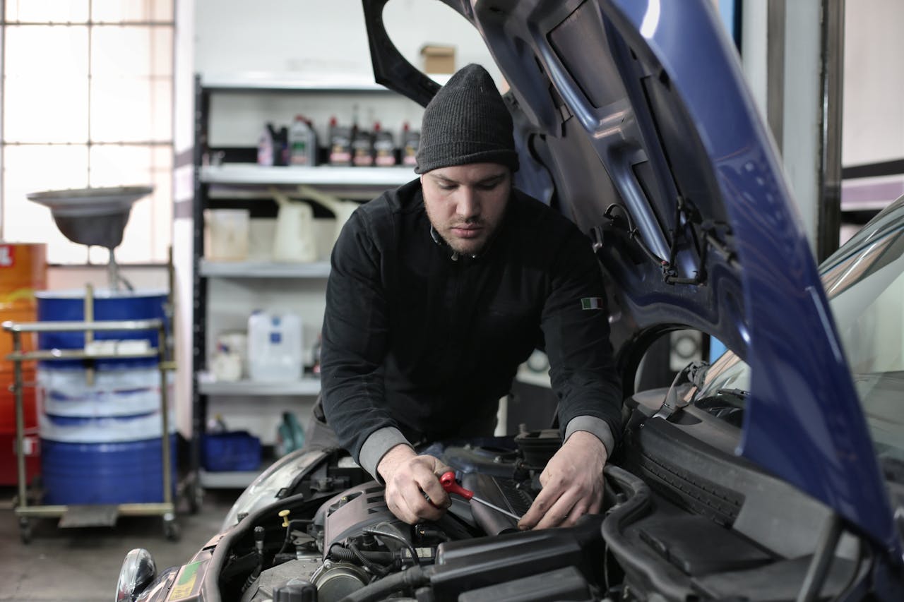 creative-03 Man working under car hood in a garage, focused on engine repair