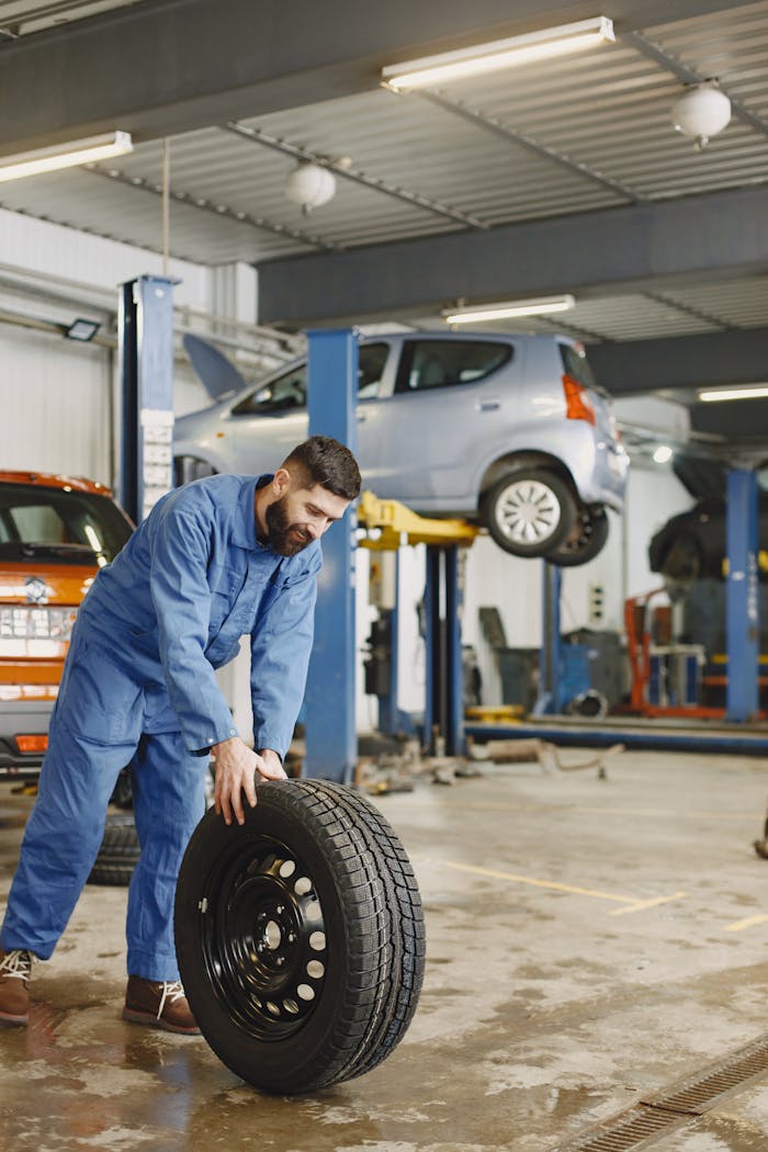 creative-03 Mechanic handling a tire in a busy automotive repair workshop.