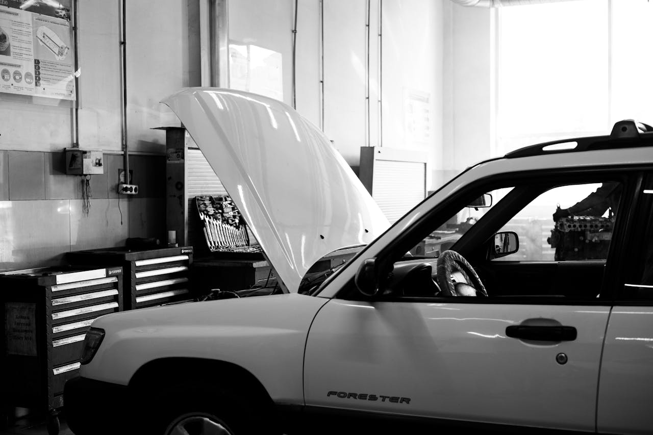 creative-02 Black and white photo of a car in an auto repair shop. Hood open for maintenance.